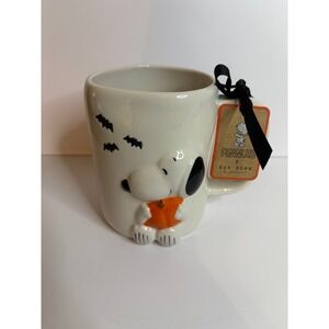 Rae Dunn Peanuts Halloween ceramic coffee mug featuring Snoopy holding a pumpkin